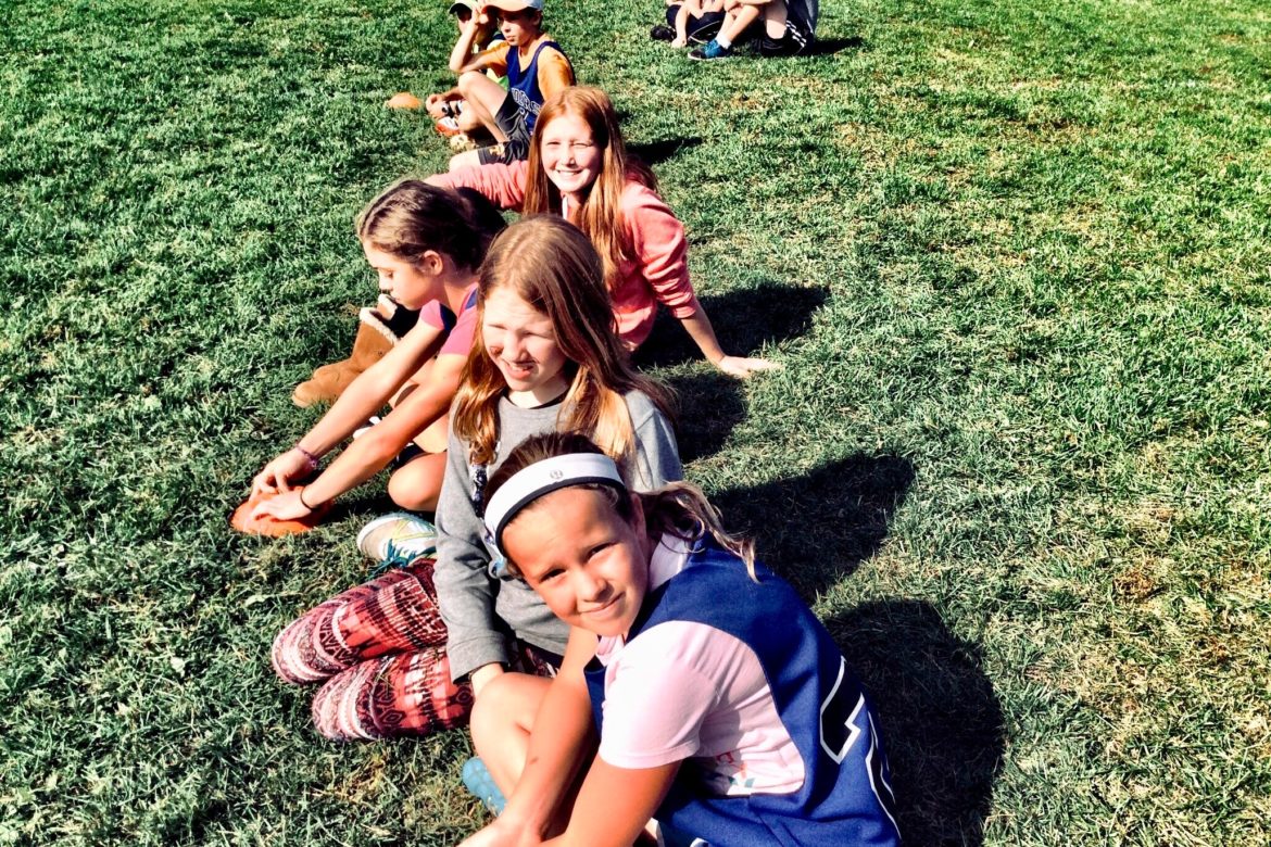 School children sitting on the grass.